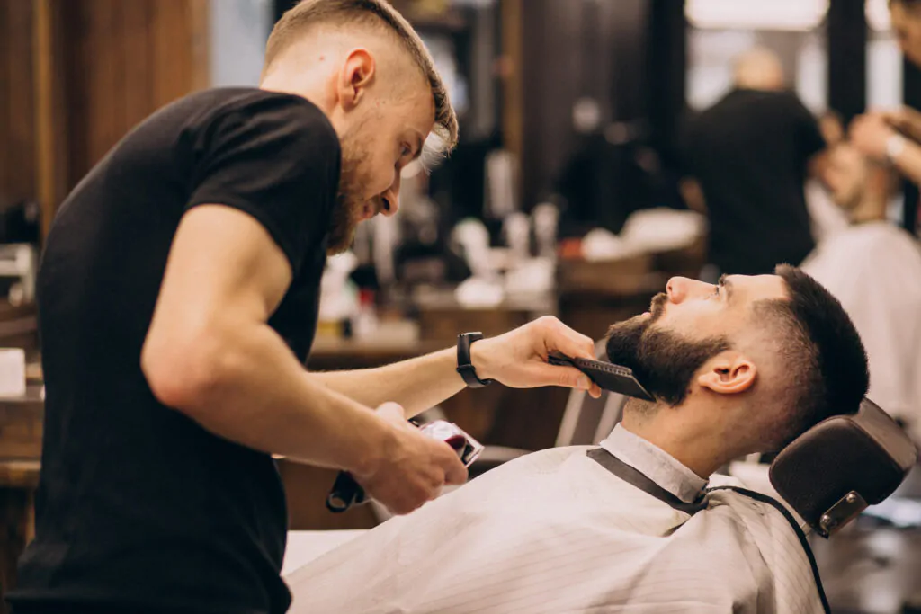 homem em um salao de barbearia fazendo o corte de cabelo e barba